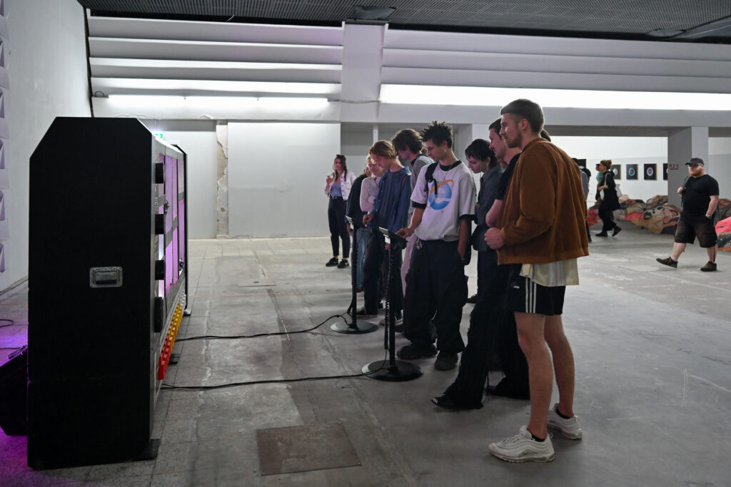 Ausstellungsansicht, TECHNO WORLDS, Besucher*innen vor der Arbeit von Moritz Simon Geist, Ausstellungseröffnung 4.05.24, Foto: Anja Schneider